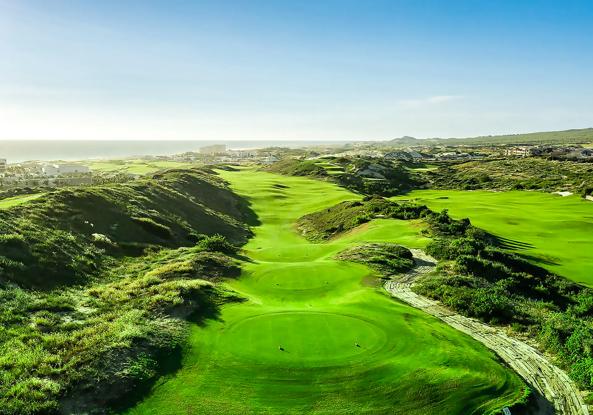 Spectacular aerial view of Diamante Dunes Course showing dramatic rolling terrain and vibrant green fairways